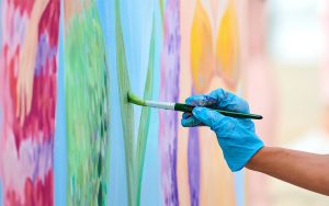 A imagem mostra uma pessoa fazendo pintura mural.