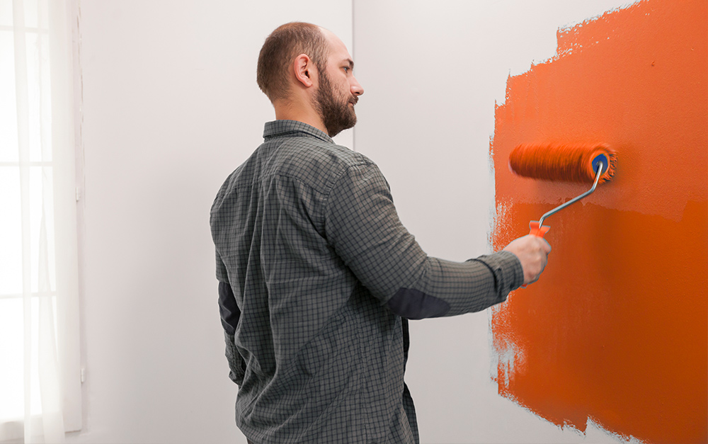 Homem pintando a parede da sua casa, utilizando alguns tipos de cores.